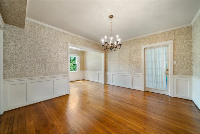 a view of an empty room with wooden floor and chandelier