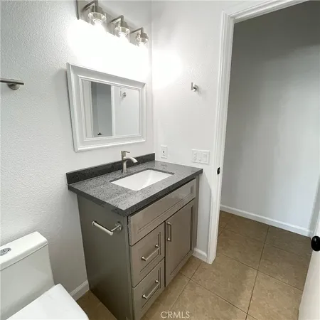 a bathroom with a granite countertop sink and a toilet