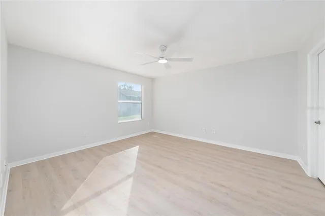 an empty room with a window and a ceiling fan