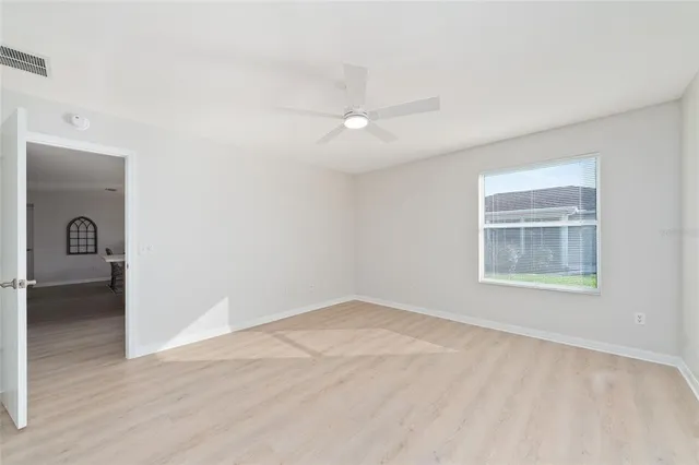 a view of an empty room with wooden floor and a window