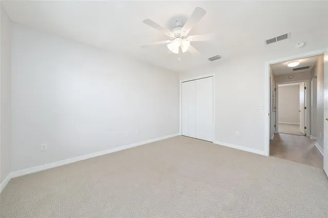 an empty room with a chandelier fan and a fireplace