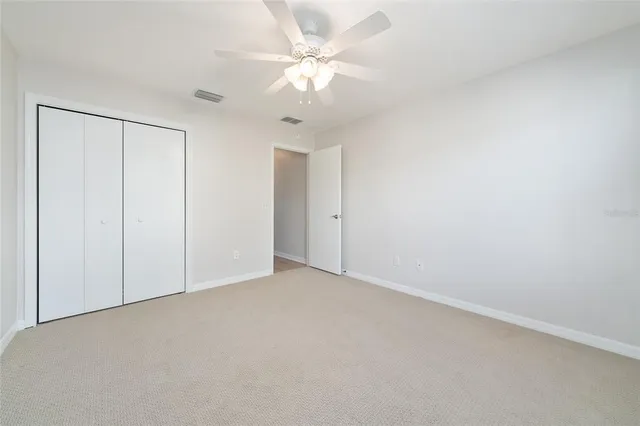 an empty room with a chandelier fan and closet area
