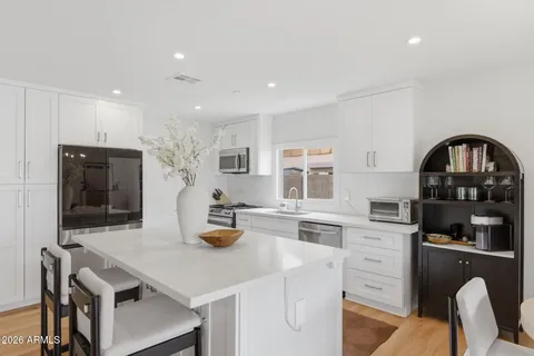 a kitchen with stainless steel appliances granite countertop a stove top oven a sink dishwasher and white cabinets with wooden floor