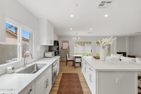 a large white kitchen with a sink and large window