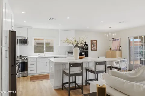 a kitchen with stainless steel appliances kitchen island granite countertop a stove a sink a dining table and chairs