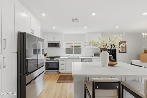 a kitchen with a refrigerator a stove a sink and dishwasher with wooden floor
