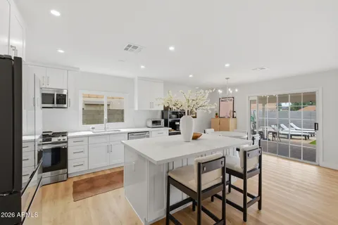a kitchen with stainless steel appliances granite countertop dining table chairs stove refrigerator and wooden floor