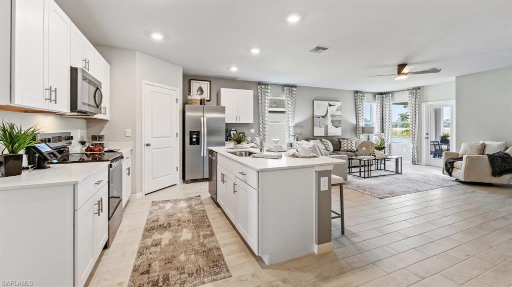 17752 Shade Tree Loop Punta Gorda, FL 33982 - Photo 40 of 40 Model Photo -Kitchen with appliances with stainless steel finishes, open floor plan, white cabinetry, a kitchen island with sink, and recessed lighting