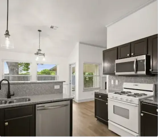 a kitchen with stainless steel appliances granite countertop a sink and stove top oven
