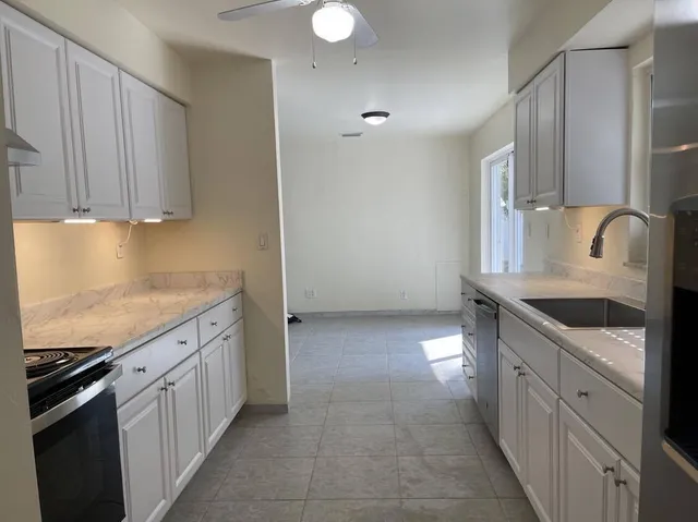 a kitchen with granite countertop a sink stove and cabinets