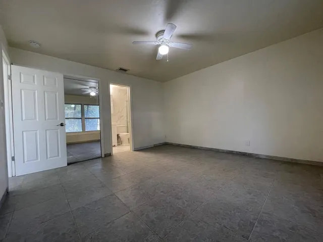 an empty room with chandelier fan and windows