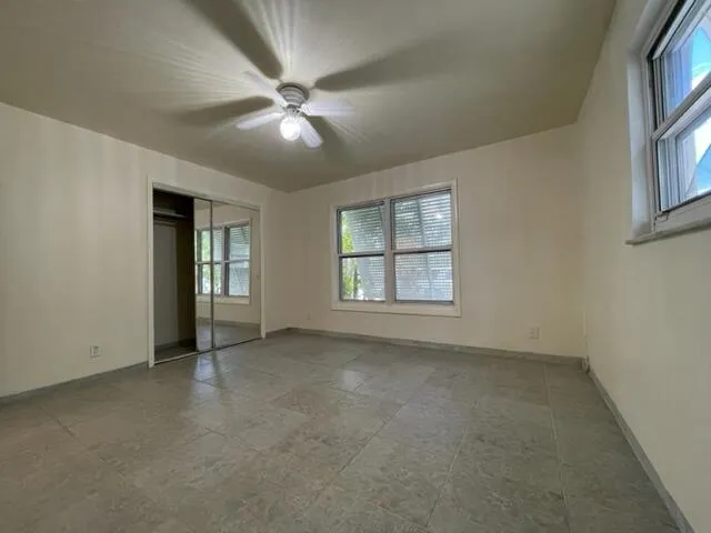 an empty room with windows and fan