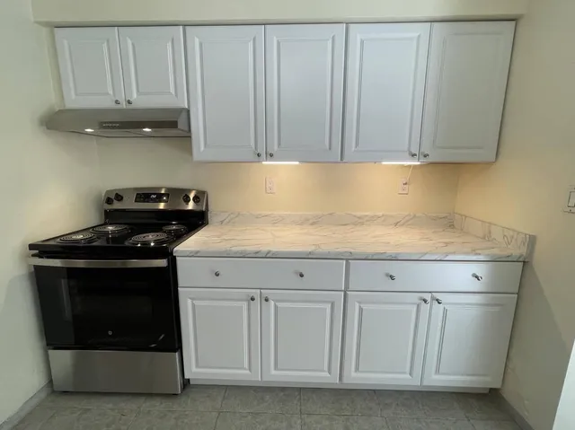 a kitchen with white cabinets and a stove with a sink