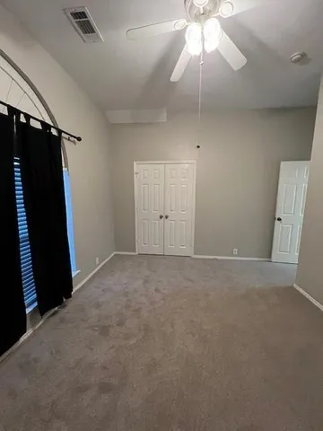 en empty room with windows and ceiling fan