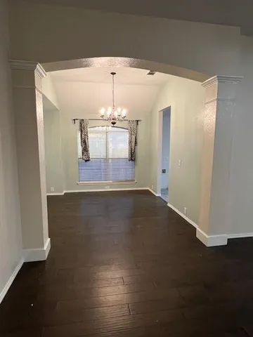 an empty room with wooden floor and chandelier fan