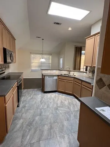 a large kitchen with stainless steel appliances a sink and cabinets