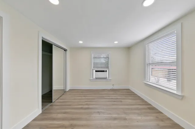 a view of empty room with wooden floor and fan