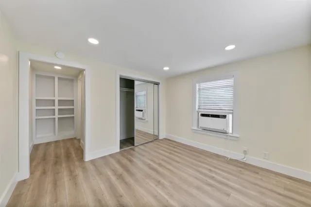 a view of empty room with wooden floor and window