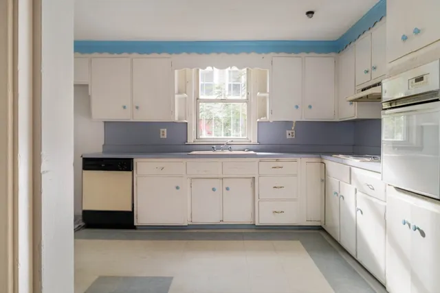 a kitchen with granite countertop white cabinets white appliances and a window