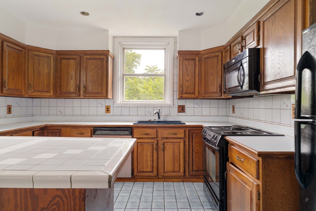 18 Westminster Avenue Boston, MA 02119 - Photo 19 of 37 a kitchen with stainless steel appliances granite countertop a sink stove and cabinets
