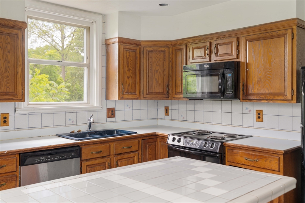 18 Westminster Avenue Boston, MA 02119 - Photo 21 of 37 a kitchen with stainless steel appliances a stove sink microwave and cabinets