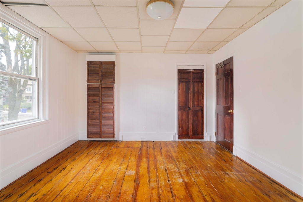 18 Westminster Avenue Boston, MA 02119 - Photo 22 of 37 a view of an empty room with wooden floor and a window