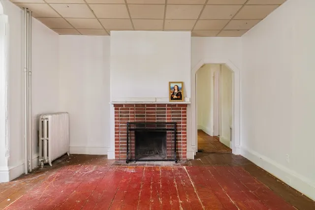 a view of empty room with a fireplace and wooden floor