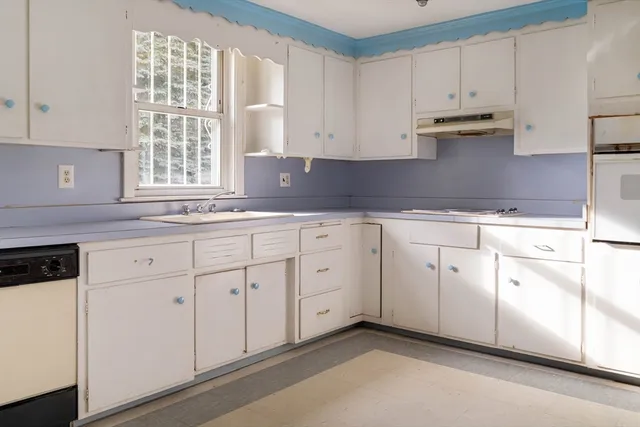 a kitchen with white cabinets white appliances and sink