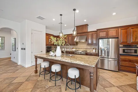 a kitchen with stainless steel appliances granite countertop table chairs and wooden cabinets
