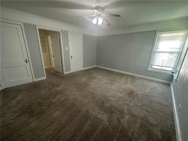 an empty room with a chandelier fan and closet area