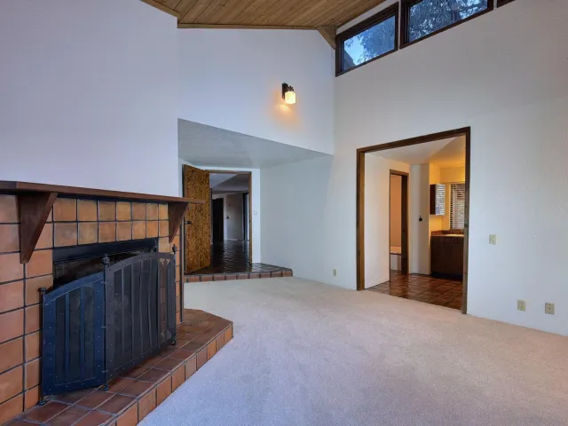 a view of a hallway to an empty room with wooden floor and a window
