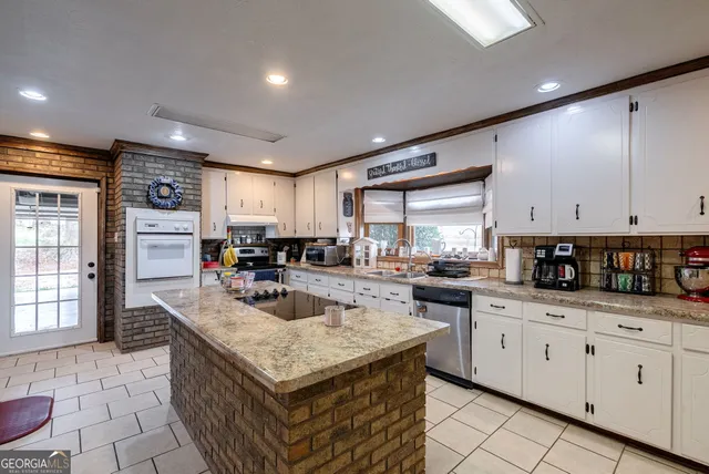 a kitchen with stainless steel appliances granite countertop a lot of counter space cabinets and a window