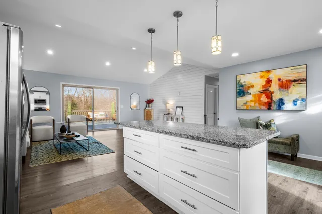 a large kitchen with stainless steel appliances kitchen island granite countertop a sink counter space cabinets and a wooden floor