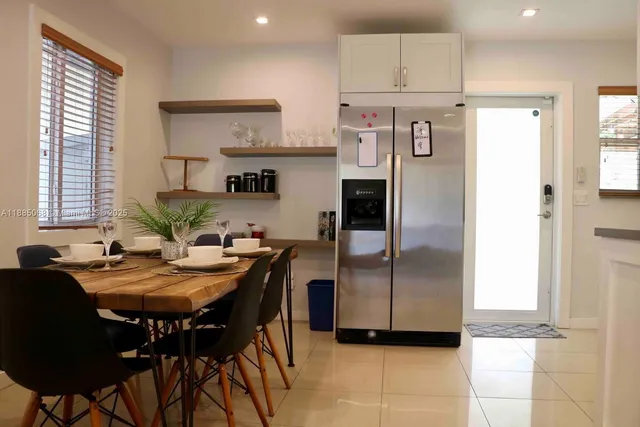 a kitchen with stainless steel appliances granite countertop a refrigerator a sink a stove and white cabinets with wooden floor