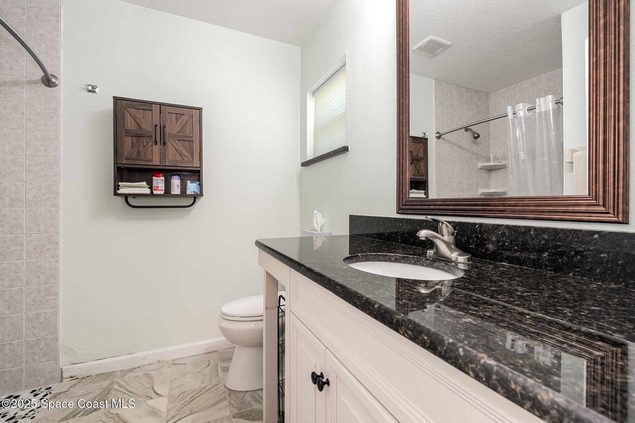 6786 U.S. Rte 1 Mims, FL 32754 - Photo 14 of 33 a bathroom with a granite countertop toilet a sink and a mirror