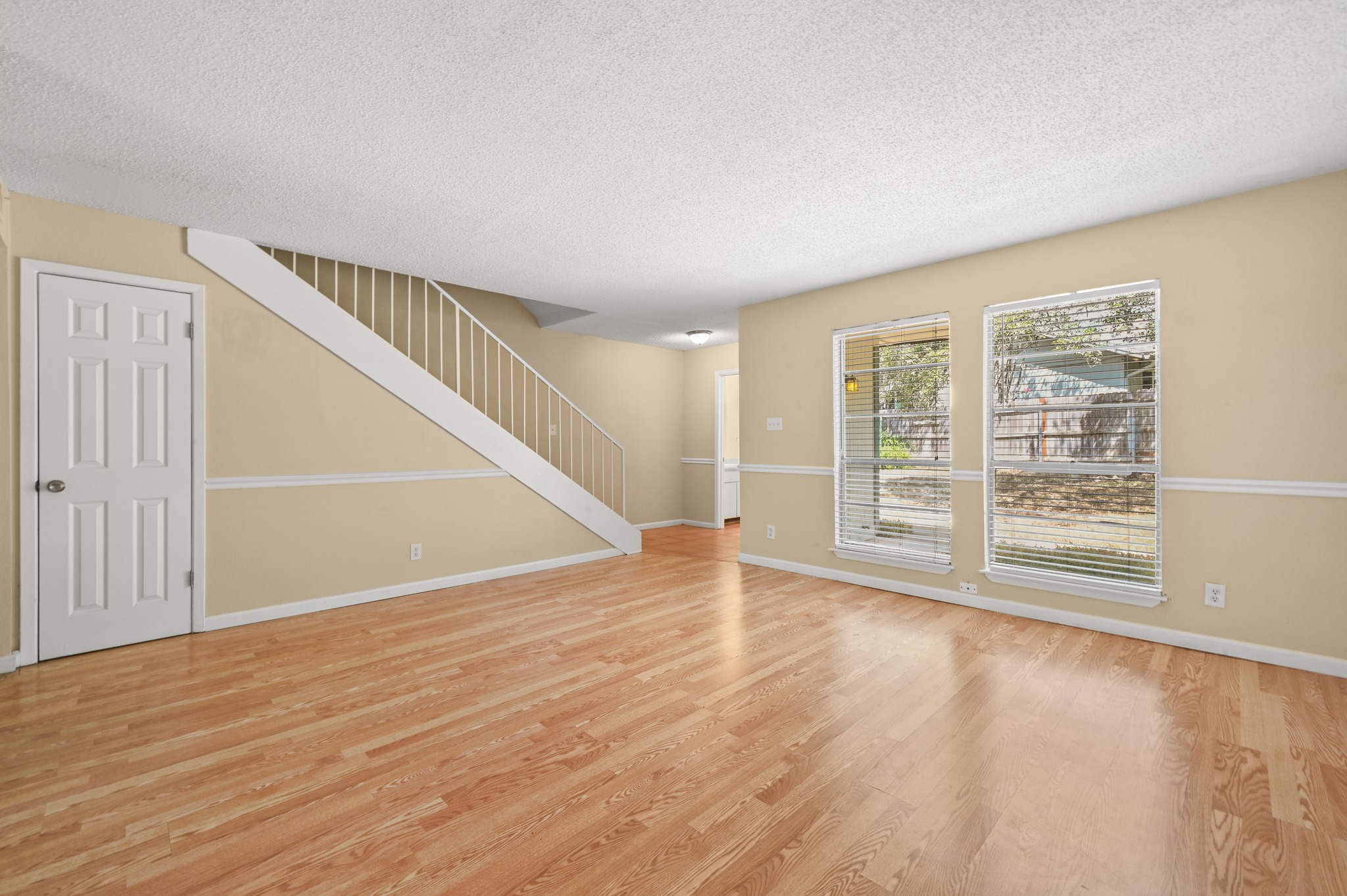 807 Castle Ridge Road, Unit C Austin, TX 78746 - Photo 9 of 26 Warm hardwood floors and tall windows define this open living space with staircase detail.