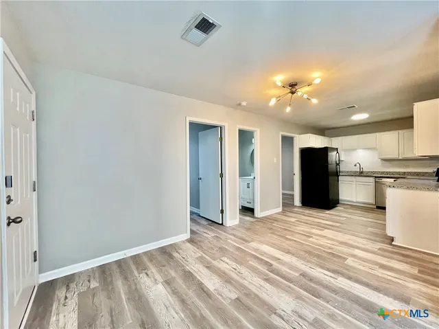 a view of a kitchen with wooden floor and a refrigerator