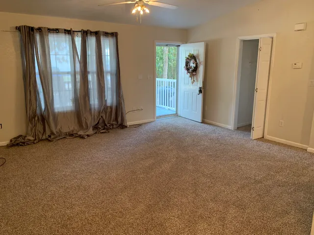an empty room with a chandelier fan and a window