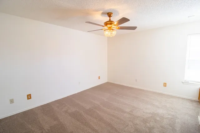 an empty room with a chandelier fan and closet