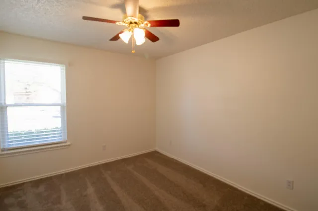 an empty room with a window and a fan
