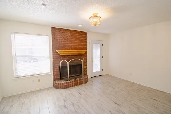 an empty room with a fireplace and wooden floor
