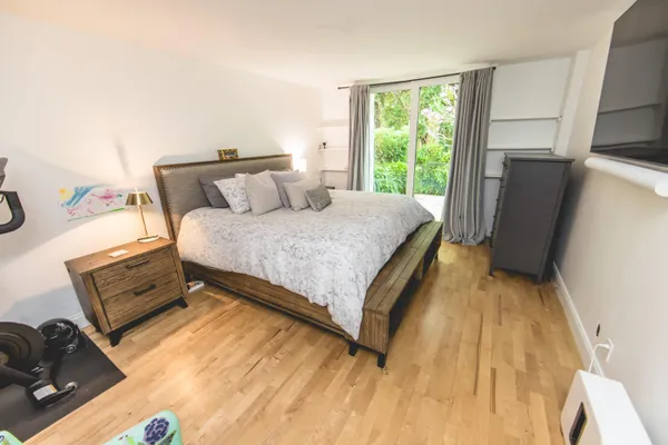 a bedroom with a bed and a flat tv screen next to a window