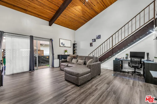 a living room with furniture and stairs with wooden floor