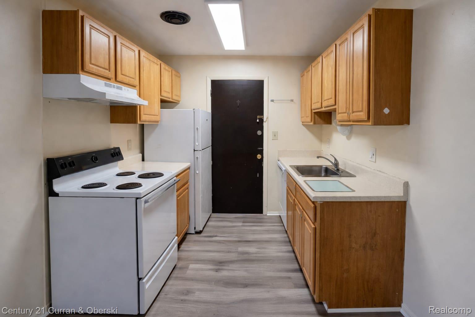 6015 Southfield Road, Unit 8 Detroit, MI 48228 - Photo 9 of 13 Kitchen featuring white appliances, light countertops, and light wood finished floors