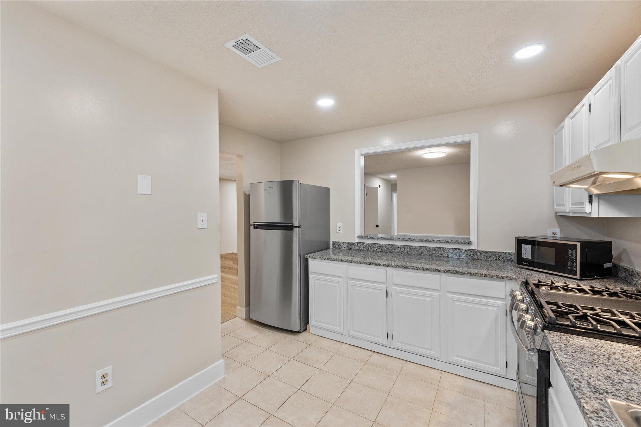 10066 Oakton Terrace Road, Unit 10066 Oakton, VA 22124 - Photo 11 of 27 a kitchen with white cabinets and stainless steel appliances