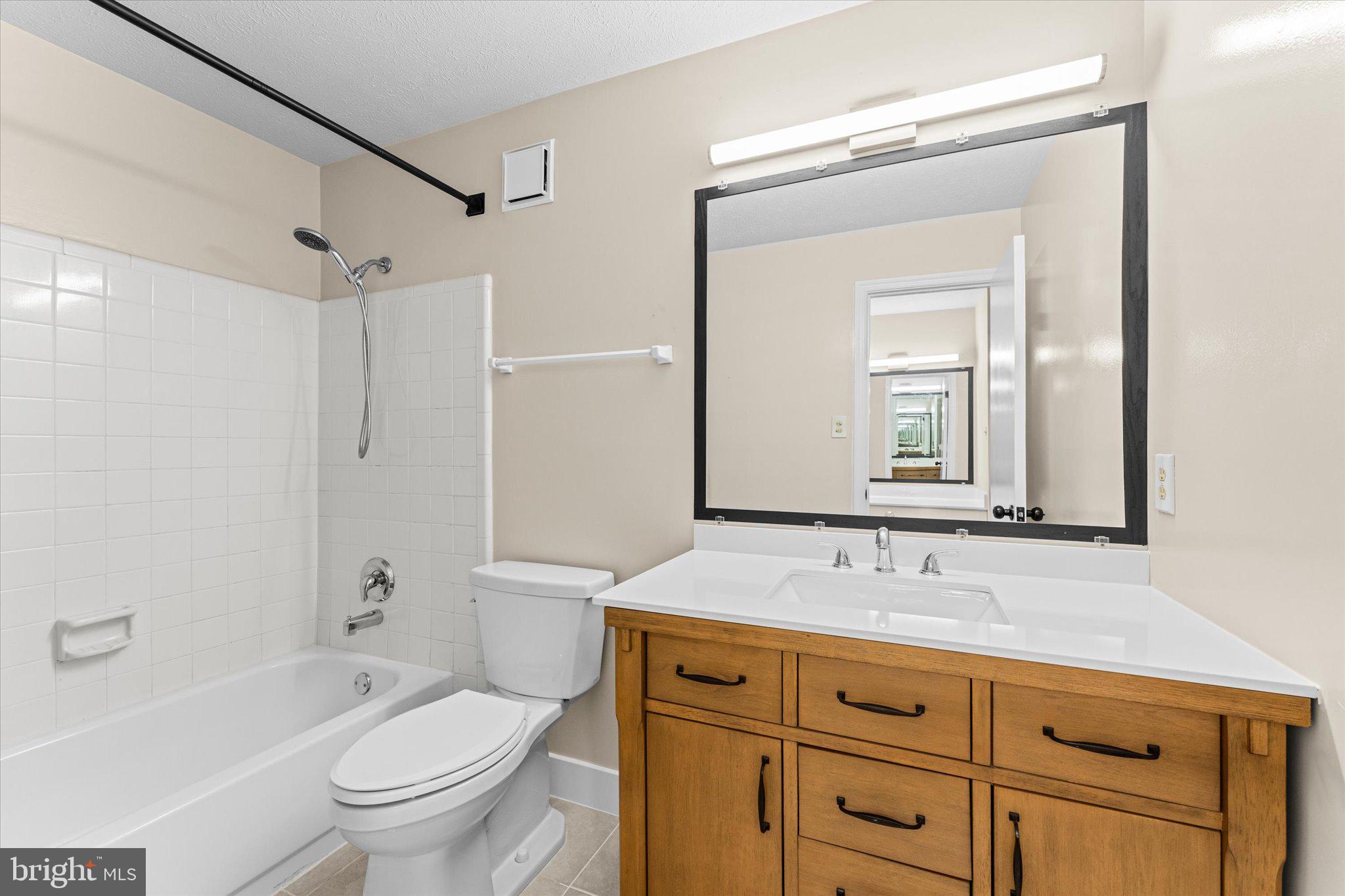 10066 Oakton Terrace Road, Unit 10066 Oakton, VA 22124 - Photo 16 of 27 a bathroom with a granite countertop toilet a sink a mirror a bathtub and shower
