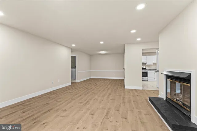 an empty room with wooden floor fireplace and windows