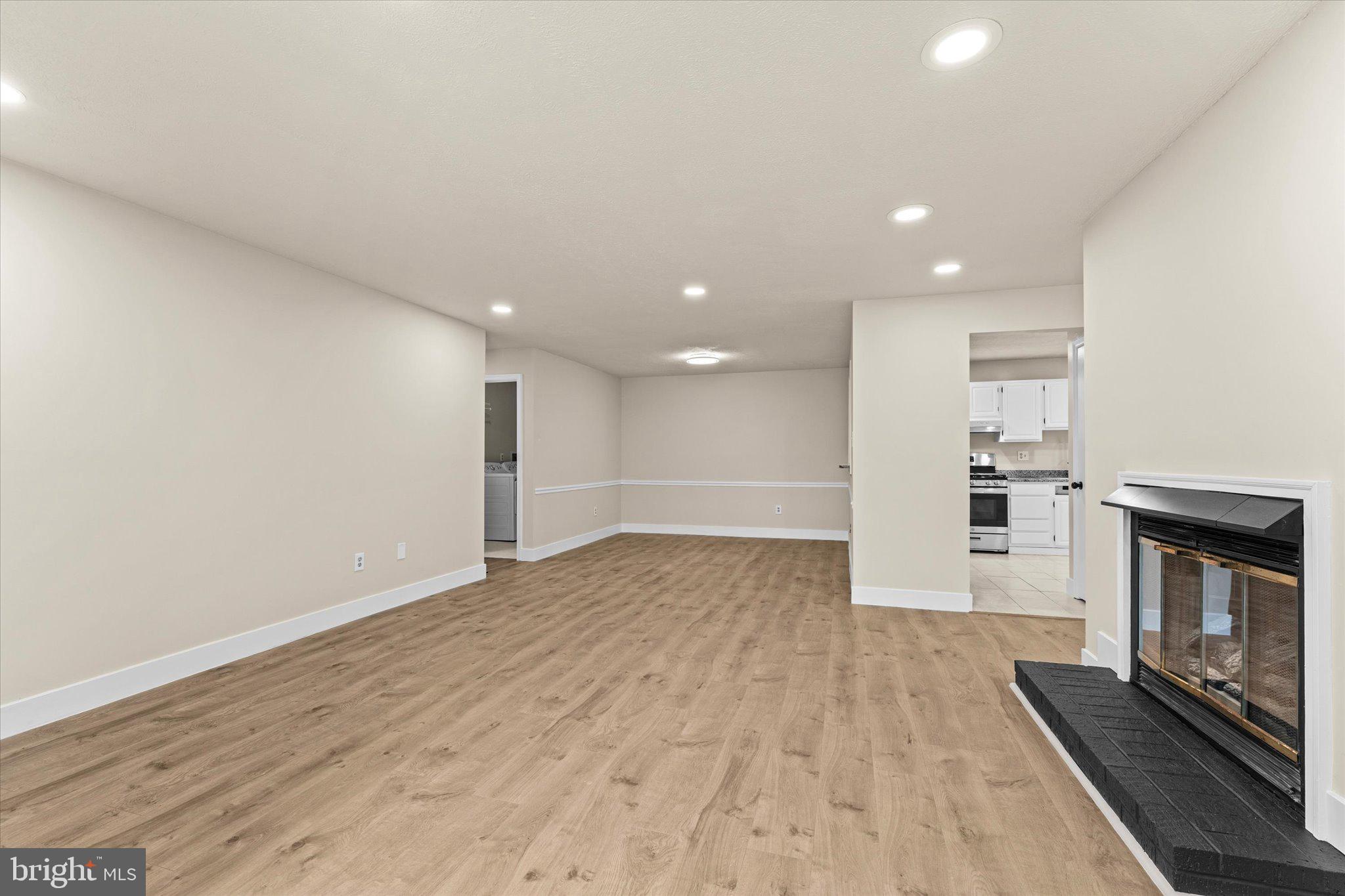 10066 Oakton Terrace Road, Unit 10066 Oakton, VA 22124 - Photo 3 of 27 an empty room with wooden floor fireplace and windows