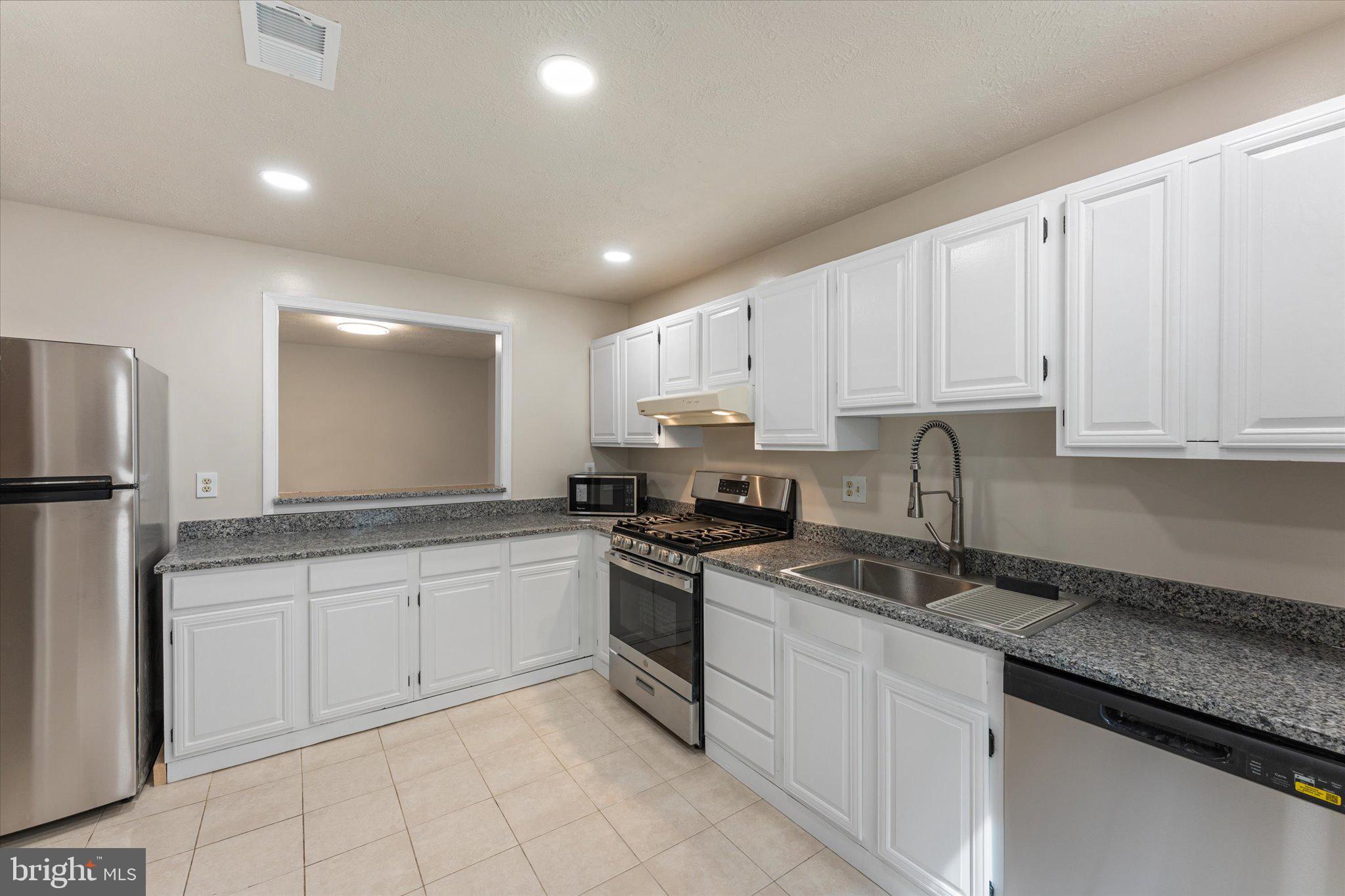 10066 Oakton Terrace Road, Unit 10066 Oakton, VA 22124 - Photo 9 of 27 a kitchen with granite countertop white cabinets and stainless steel appliances