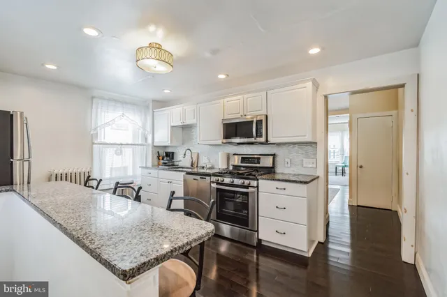 a kitchen with stainless steel appliances granite countertop a stove top oven a sink dishwasher and a refrigerator with wooden floor